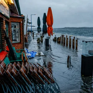 Die Straße vor den Cafés und Geschäften am Tiessenkai im Kieler Stadtteil Holtenau ist vollständig von der Ostssee überflutet.