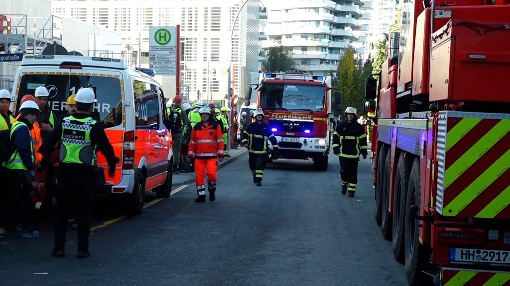 Feuerwehrkräfte stehen vor dem Eingang der Baustelle.