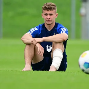 Anssi Suhonen sitzt nachdenklich auf dem Rasen