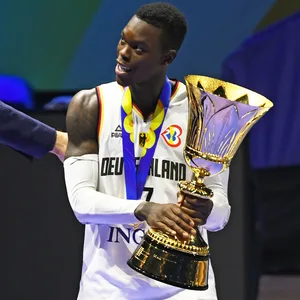Dennis Schröder mit der Goldmedaille um den Hals und dem WM-Pokal in den Händen.