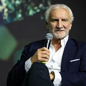Rudi Völler mit einem Mikrofon in der Hand.