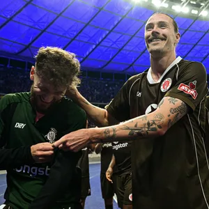 Jackson Irvine mit Marcel Hartel vor der Fankurve im Olympiastadion