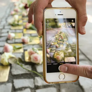 Eine Frau fotografiert Stolpersteine mit ihrem Handy. (Symbolbild)