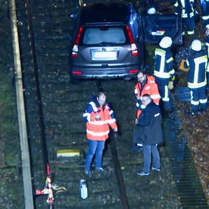 Rettungsleute stehen an dem Auto, mit dem ein 84-Jähriger aus Hamburg am Montagabend bei Ahrensburg auf den Bahngleisen der U1 gefahren ist.