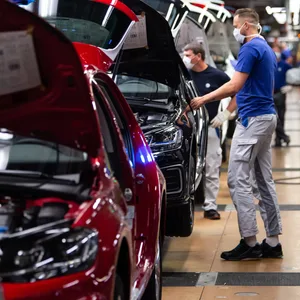 VW-Angestellte arbeiten in der Produktion in Wolfsburg an einem Fahrzeug. (Symbolbild)