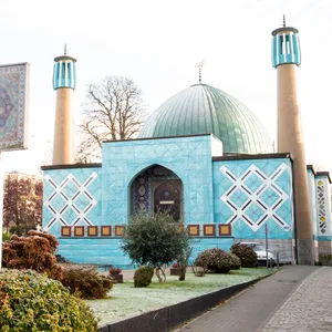 Eine blaue Moschee - die Imam-Ali-Moschee- , vor der ein Schild steht.