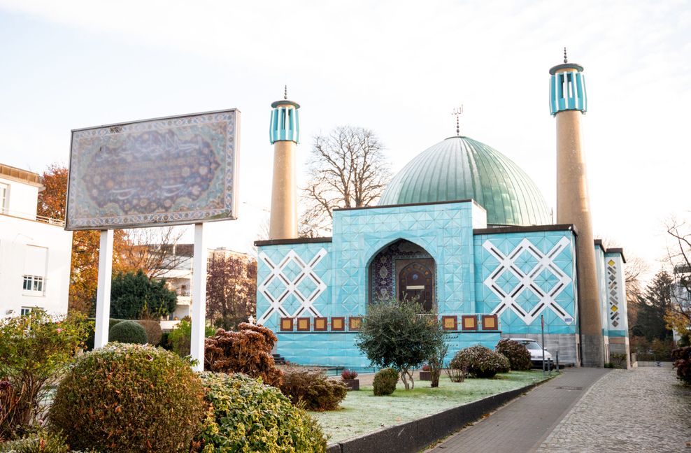 Eine blaue Moschee - die Imam-Ali-Moschee- , vor der ein Schild steht.