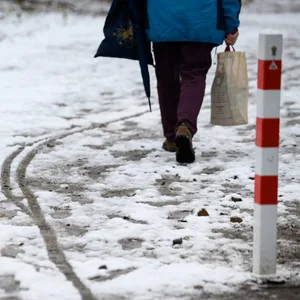 Eine Person läuft einen mit Schneematsch bedeckten Weg entlang. (Symbolbild)