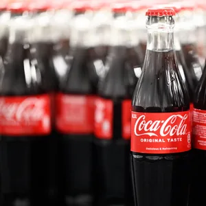 Am Produktionsstandort Mannheim von Coca-Cola Europacific Partners - CCEP Deutschland GmbH werden abgefüllte 0,33 Liter Mehrweg Glas Coca-Cola Flaschen über ein Förderband transportiert.