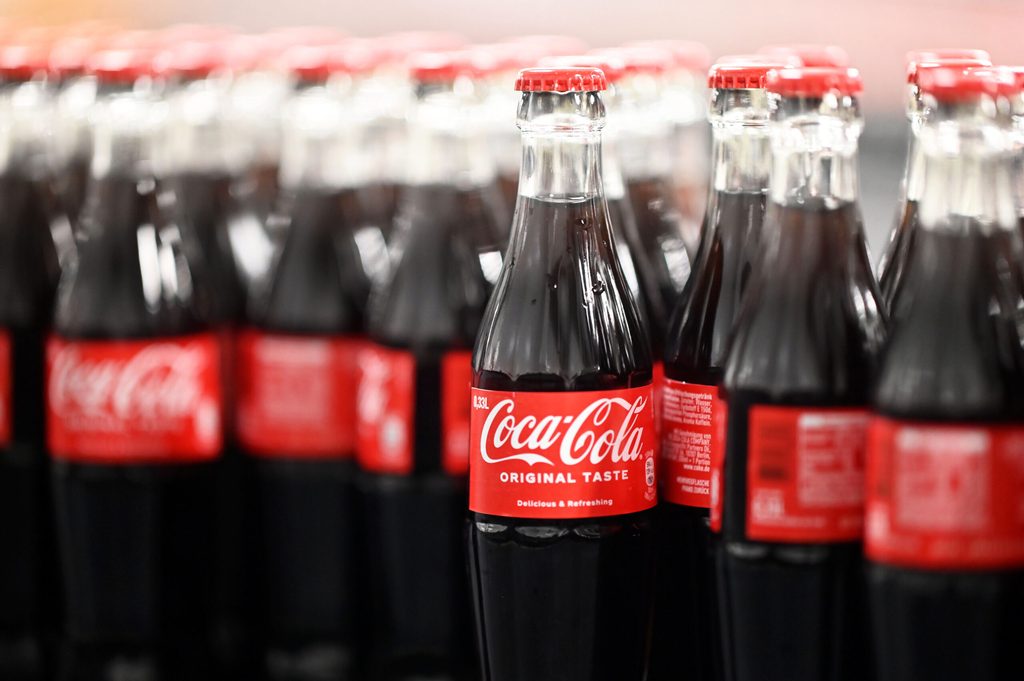 Am Produktionsstandort Mannheim von Coca-Cola Europacific Partners - CCEP Deutschland GmbH werden abgefüllte 0,33 Liter Mehrweg Glas Coca-Cola Flaschen über ein Förderband transportiert.