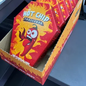 Mehrerer Packungen der „Hot Chip Challenge“ liegen bei einem Kiosk neben der Kasse.
