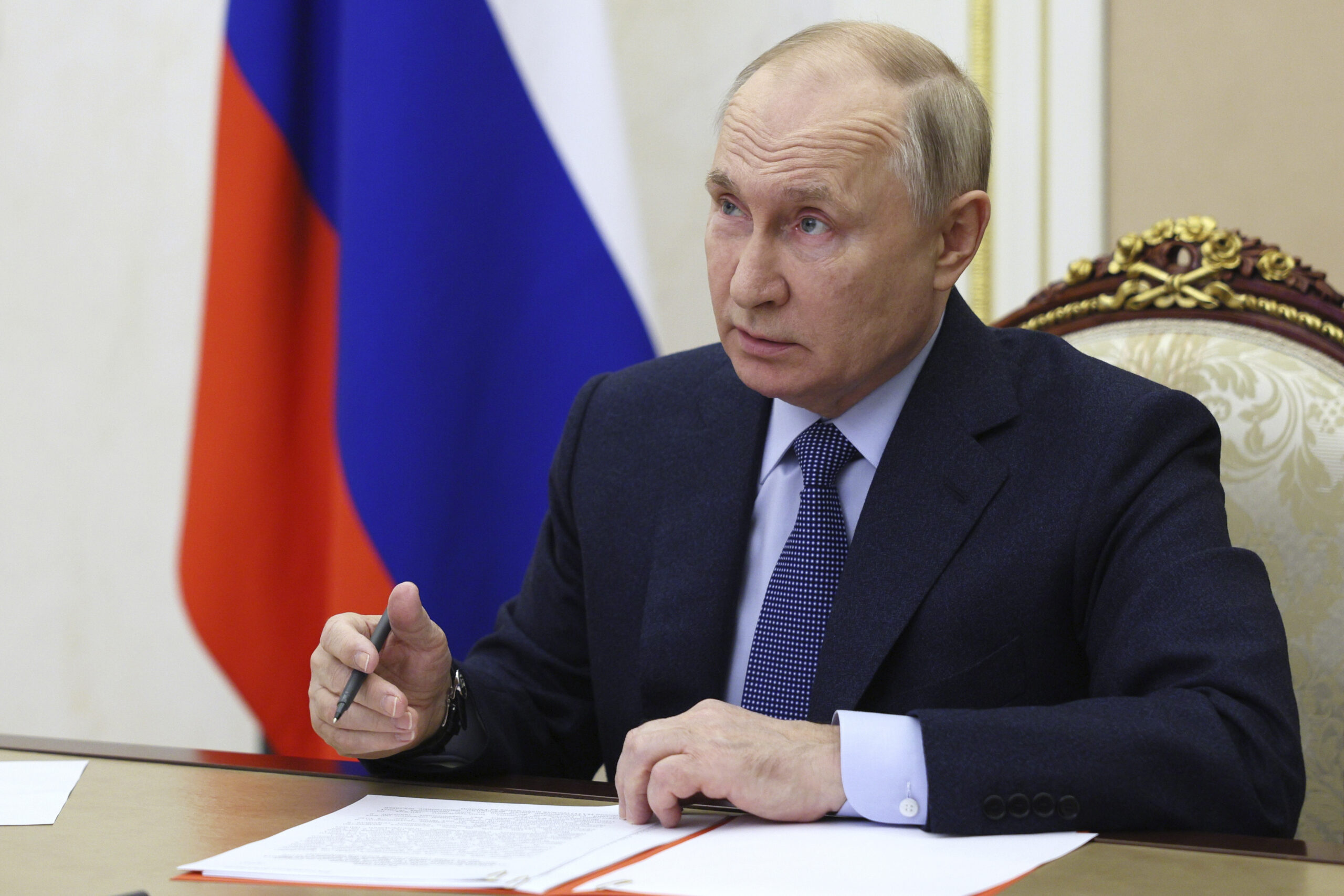 Russlands Präsident Wladimir Putin sitzt an einem Tisch und unterschreibt ein Papier