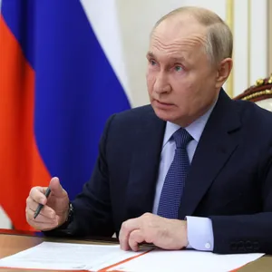 Russlands Präsident Wladimir Putin sitzt an einem Tisch und unterschreibt ein Papier