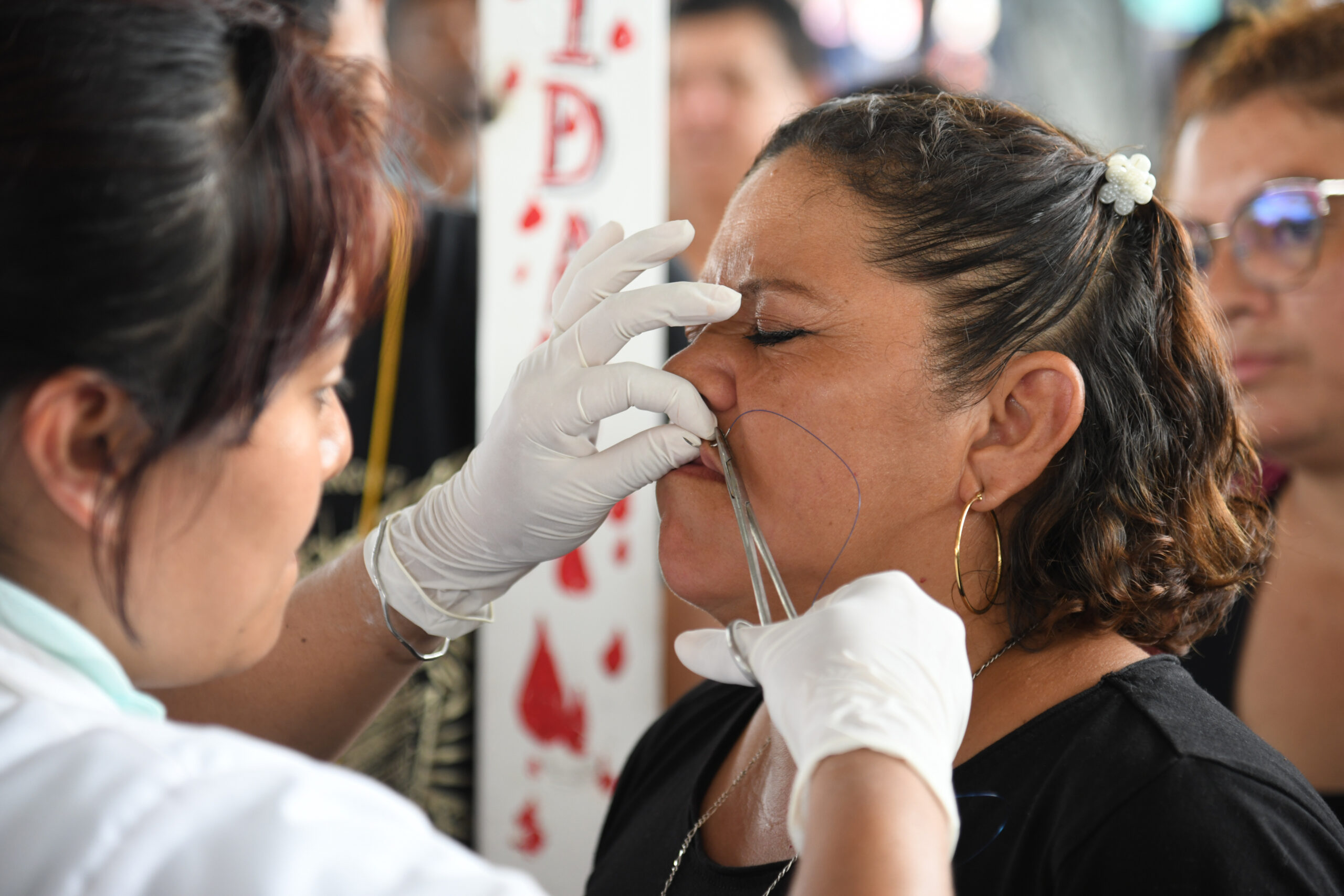 Frau aus El Salvador lässt sich während eines Protests die Lippen zunähen.
