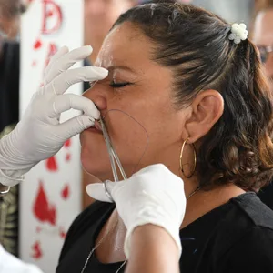 Frau aus El Salvador lässt sich während eines Protests die Lippen zunähen.