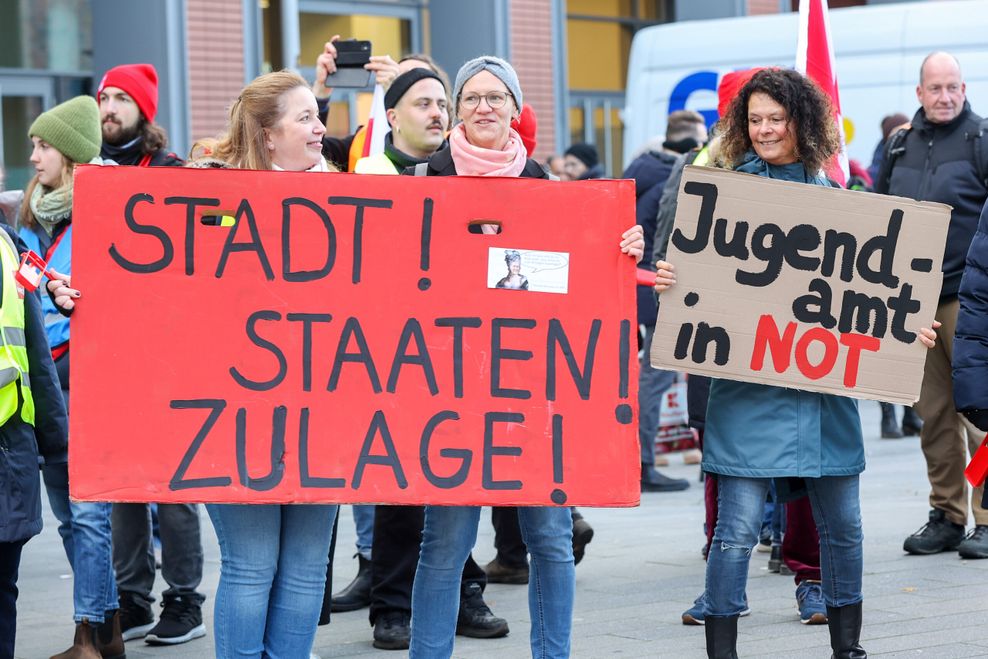 Mit Schildern und Transparenten demonstrierten Teilnehmer in Hamburg-während eines Warnstreiks. Auf den Schildern steht die Aufschrift „Stadtstaatenzulage jetzt“ und „Jugendamt in Not“. (Archivbild)