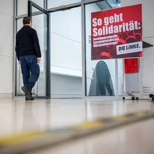 Ein Mitarbeiter des Bundestags geht zum Sitzungssaal der Fraktion von Die Linke auf der Fraktionsebene im Bundestag neben einem Plakat mit der Aufschrift «So geht Solidarität:» .
