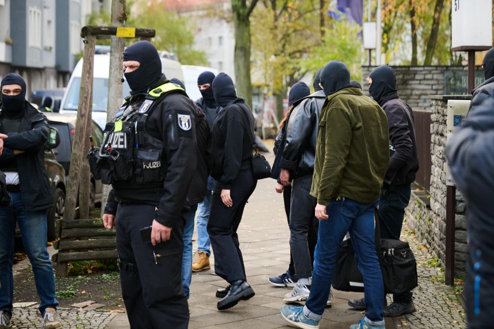Polizisten und andere Personen verlassen das Anwesen eines Gebäudes in Neukölln.