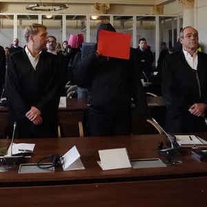 Im Prozess um die Vergewaltigung einer Jugendlichen stehen die Angeklagten neben ihren Anwälten im Gerichtssaal.