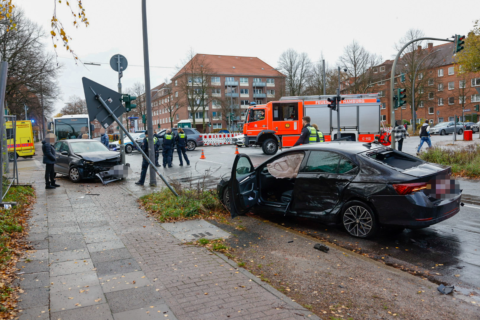 Drei nach einem Unfall beschädigte Autos stehen an der Kreuzung Krausestraße/Straßburger Straße in Hamburg. Feuerwehr, Polizei und Rettungsleute begutachten die Unfallstelle.