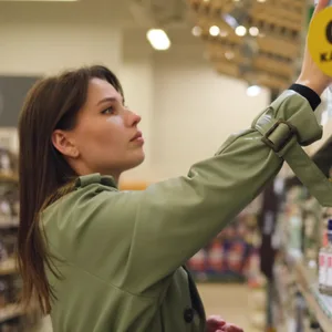 Eine Frau greift im Supermarkt nach einer Getränke-Flasche. (Symbolbild)