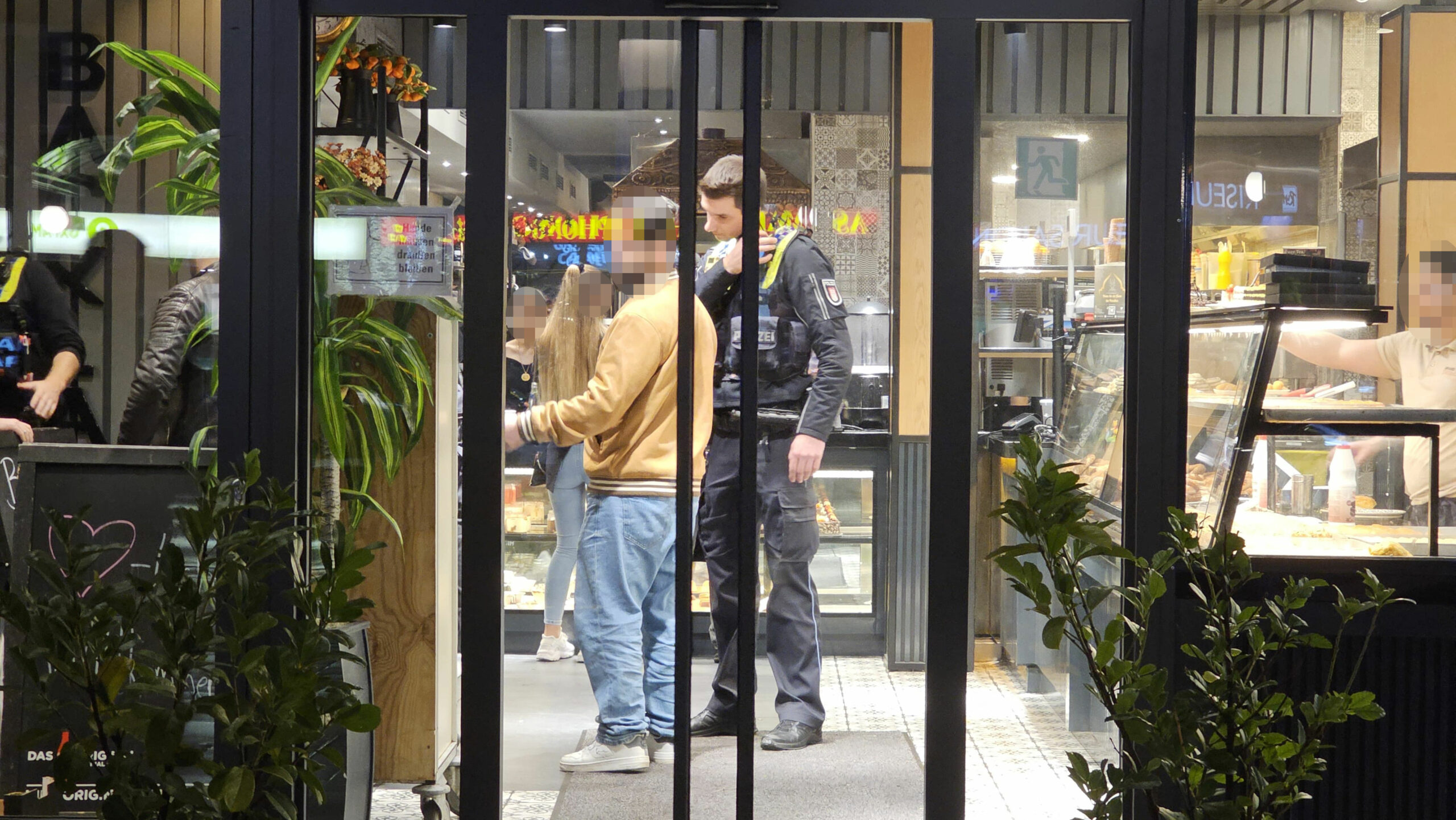 Das Café in Wandsbek, durch die Glastür sieht man Gäste und Polizisten