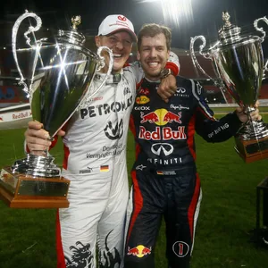 Michael Schumacher und Sebastian Vettel in Rennanzug und Pokal in der Hand