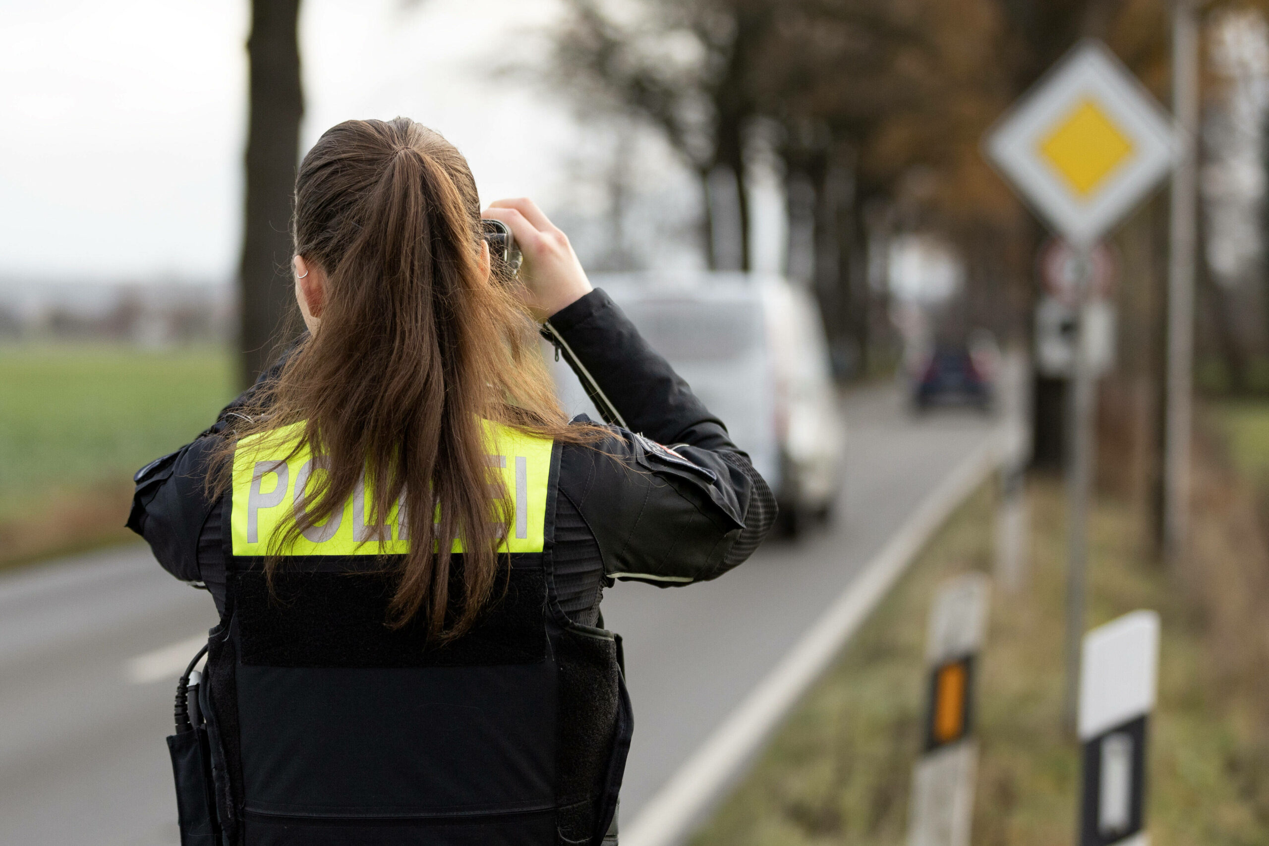 Ein Beamtin der Polizei steht mit einem Laser für die Geschwindigkeitsmessung von Fahrzeugen an einer Straße. (Symbolbild)
