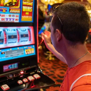 Ein Mann sitzt in einem Kasino vor einem Spielautomaten.