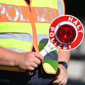 Ein Polizist steht mit einer Polizeikelle bereit.
