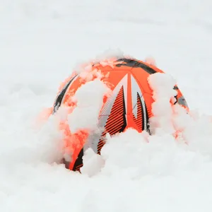 Ein roter Fußball liegt im Schnee