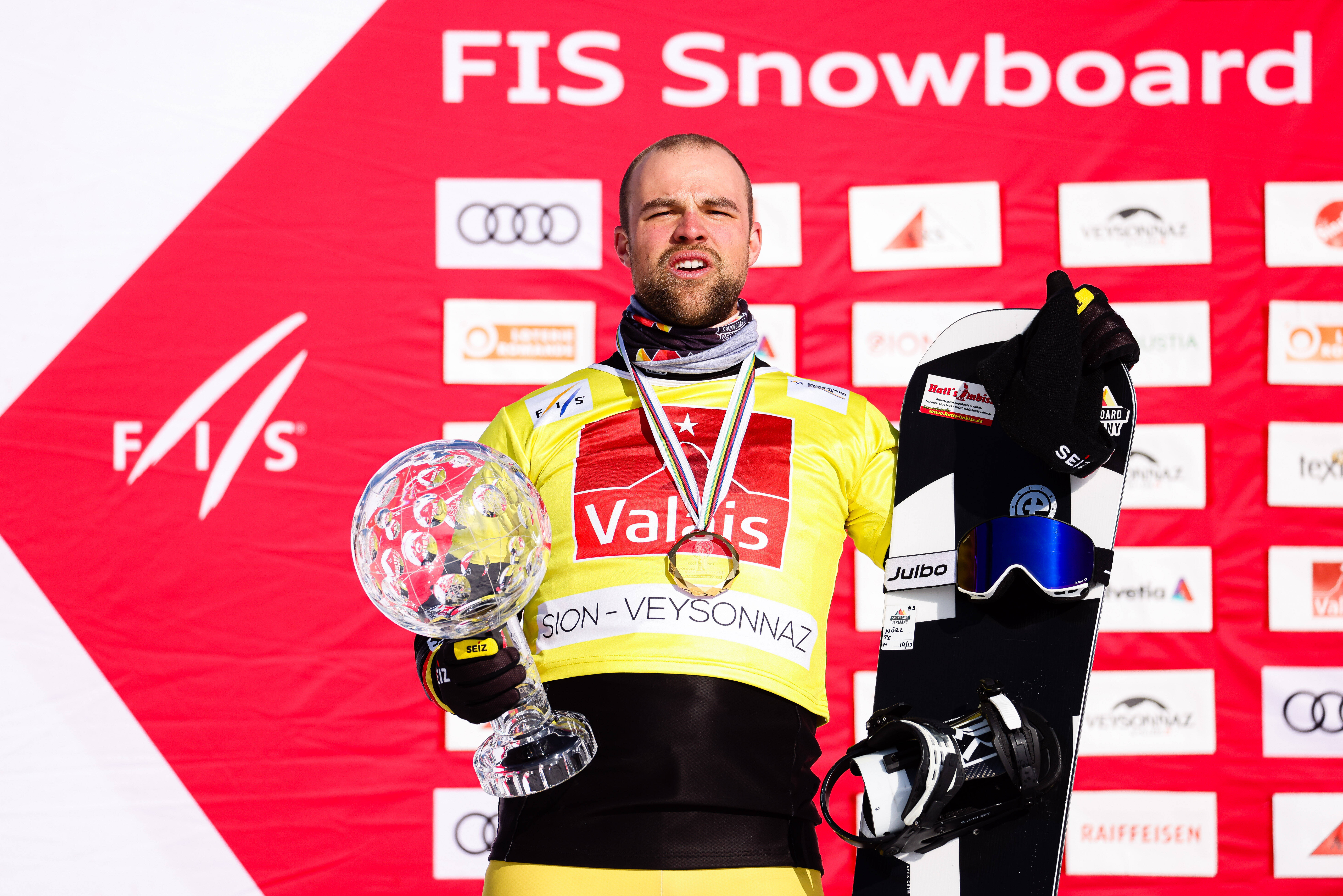 Martin Nörl mit Snowboard und der Kristallkugel des Besten Snowboarders im Weltcup