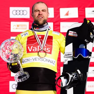 Martin Nörl mit Snowboard und der Kristallkugel des Besten Snowboarders im Weltcup