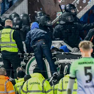 Polizei und Fans im Fanblock, davor eine Reihe von Ordnern