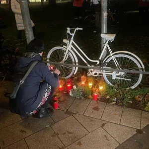 Eine Teilnehmerin entzündet eine Kerze vor dem Ghostbike.