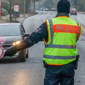 Verkehrskontrolle: Ein Polizist mit Kelle hält ein Auto an.