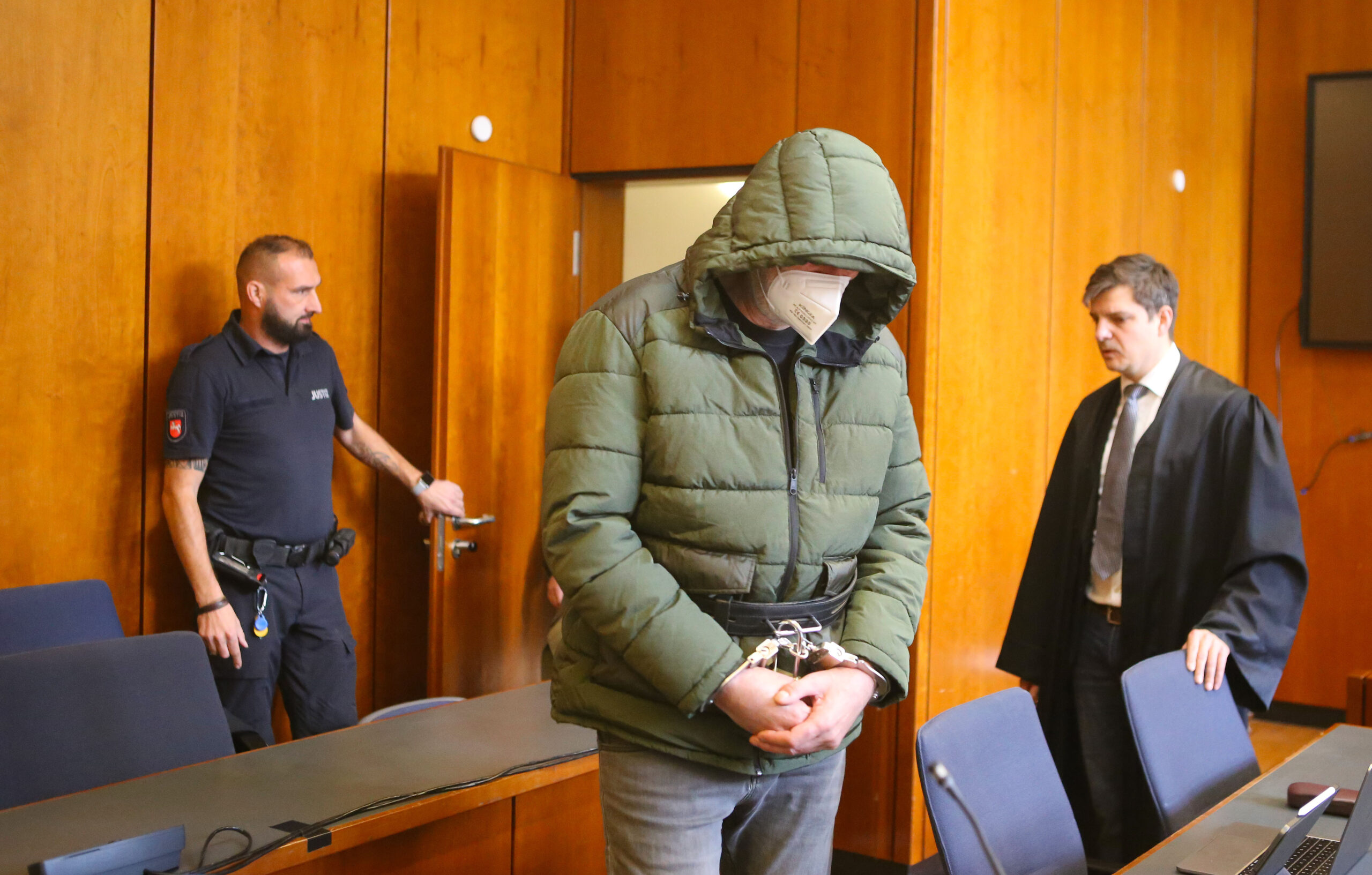 Der Angeklagte (M.) steht mit Handschellen in einem Saal des Landgerichts Göttingen neben seinem Verteidiger.