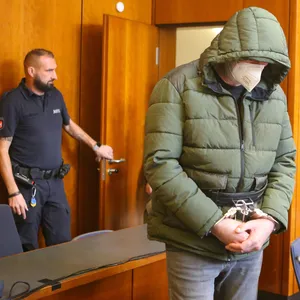 Der Angeklagte (M.) steht mit Handschellen in einem Saal des Landgerichts Göttingen neben seinem Verteidiger.