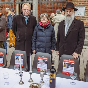 Hauptpastor Jens-Martin Kruse, Hanna Lehming und Landesrabbiner Shlomo Bistritzky (v.l.) stehen an einem Tisch. Davor Stühle, auf denen Fotos der Geiseln angebracht sind