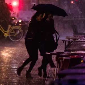 Fußgängerinnen im Hamburger Schanzenviertel bringen sich vor einem Regenschauer in Sicherheit (Archivbild).
