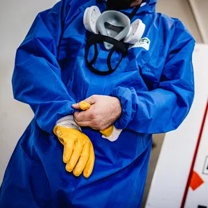 Ein Mann FFP3-Atemschutzmaske, Overall, Schutzbrille und Handschuhen