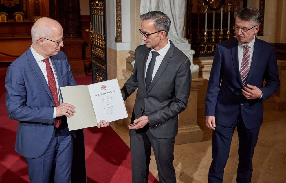 Peter Tschentscher übergibt Schnabel die Ernennungsurkunde. Rechts daneben: Der scheidende Polizeipräsident Ralf Martin Meyer.