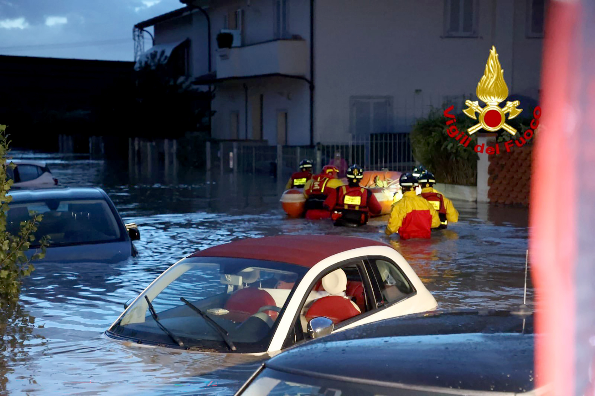 Feuerwehrleute mit einem Schlauchboot auf einer überschwemmten Straße in Lamporecchio. Von mehreren Autos ragen nur noch die Dächer aus dem Wasser.