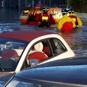 Feuerwehrleute mit einem Schlauchboot auf einer überschwemmten Straße in Lamporecchio. Von mehreren Autos ragen nur noch die Dächer aus dem Wasser.