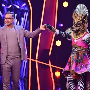 „Masked Singer“-Moderator Matthias Opdenhövel (l.) steht neben der Okapi-Figur, die als erstes in der neuen Staffel ausgeschieden ist.