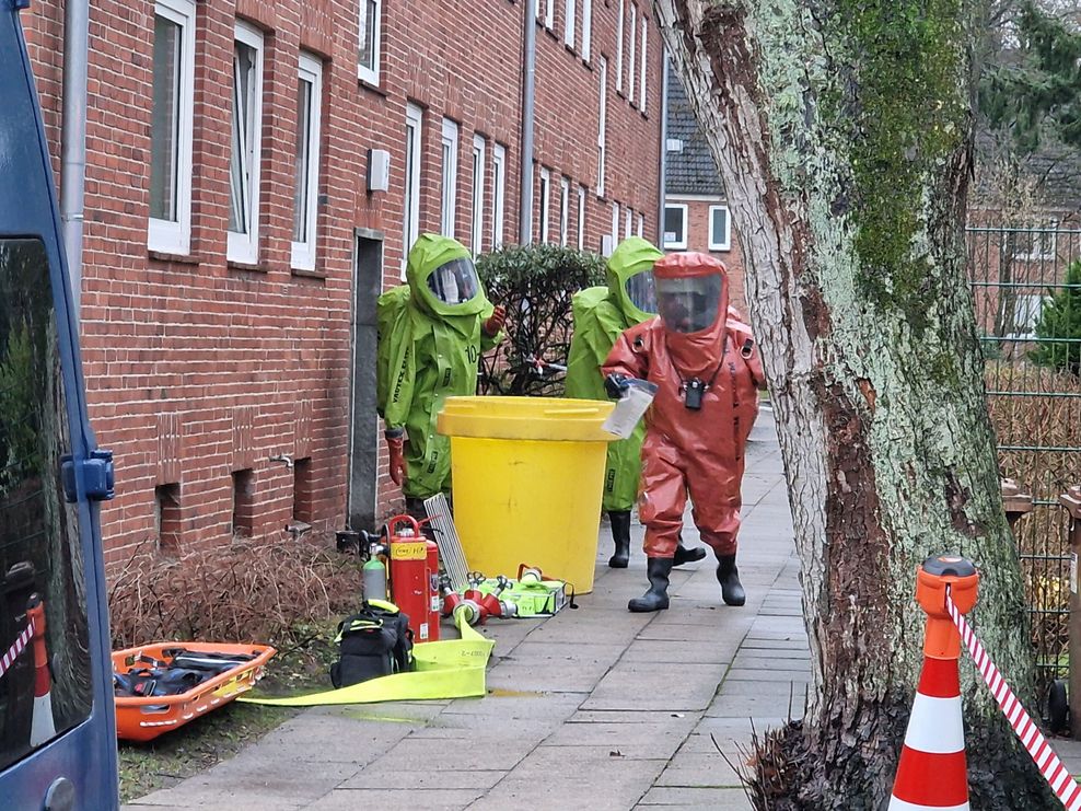 Drei Feuerwehrleute in Schutzanzügen kommen aus dem Wohnhaus