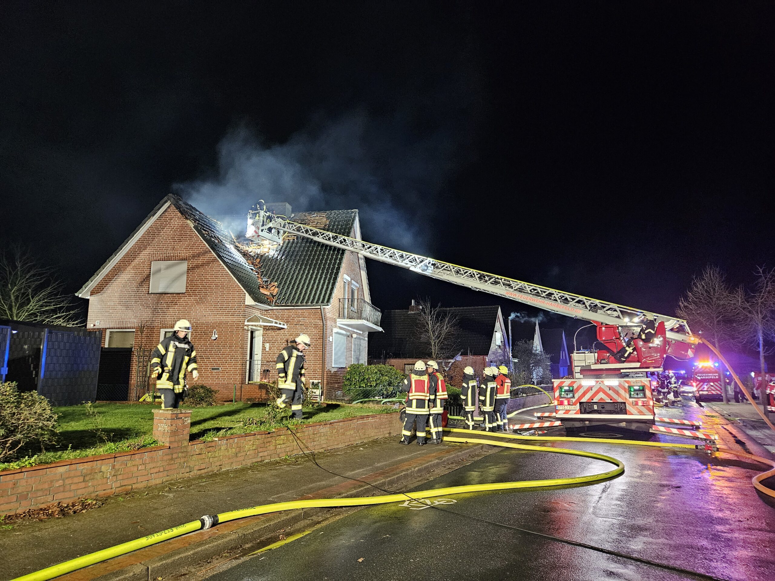 Feuerwehrleute löschen den brennenden Dachstuhl eines Einfamilienhauses