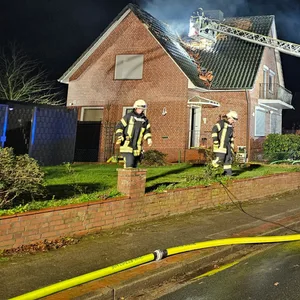 Feuerwehrleute löschen den brennenden Dachstuhl eines Einfamilienhauses