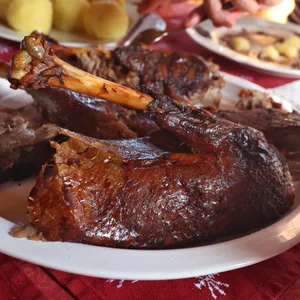 Teile einer gebratenen Weihnachtsgans liegen auf einem weihnachtlich gedeckten Tisch