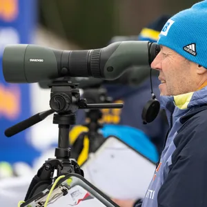 Biathlon-Trainer Uros Velepec schaut durch ein Fernrohr